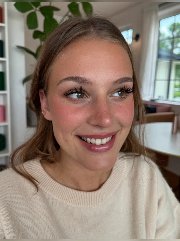 Lachende jonge vrouw met mooi gekrulde wimpers na een lash lifting